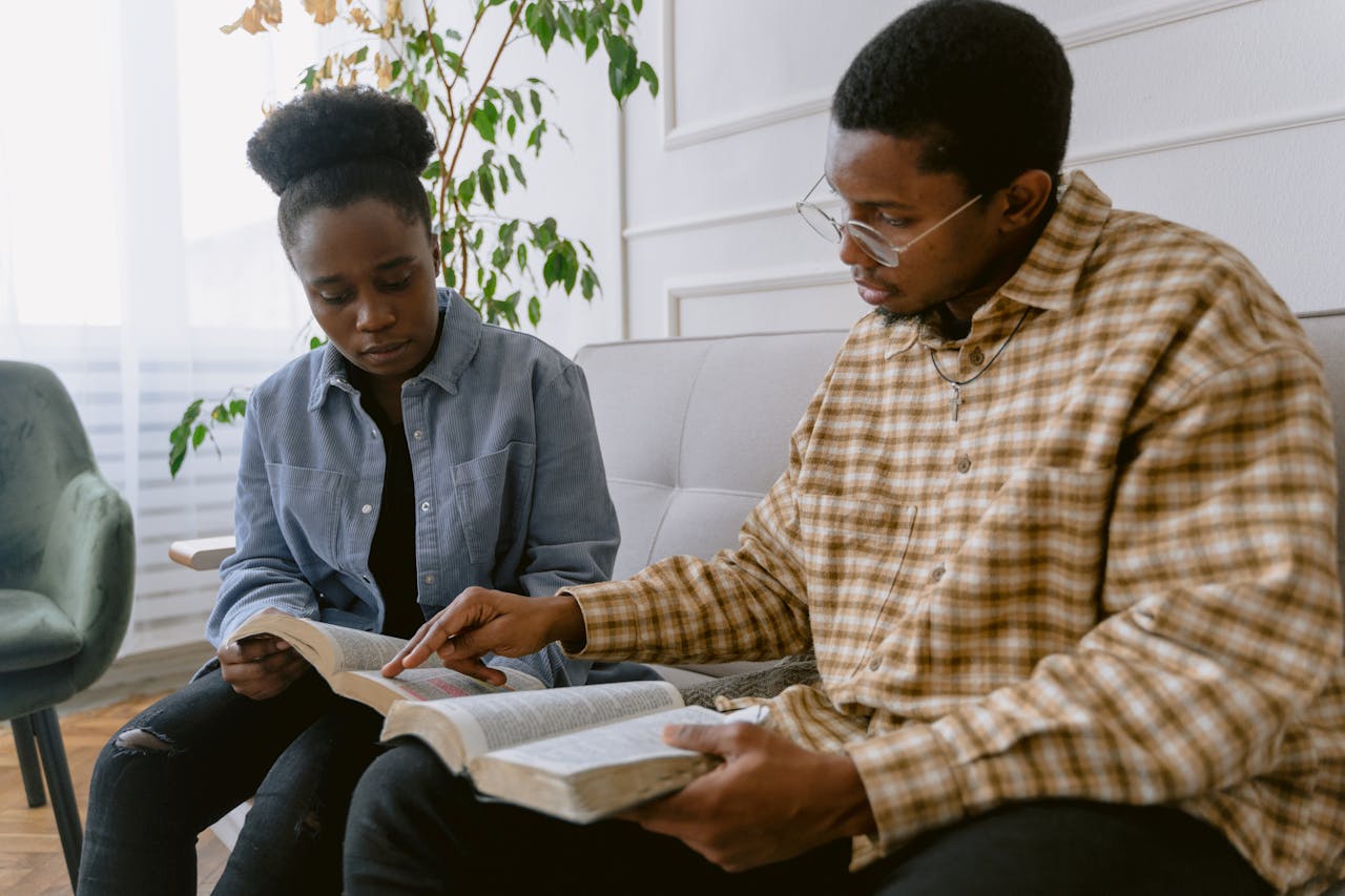 Two individuals engaged in reading the Bible together, depicting faith and togetherness.